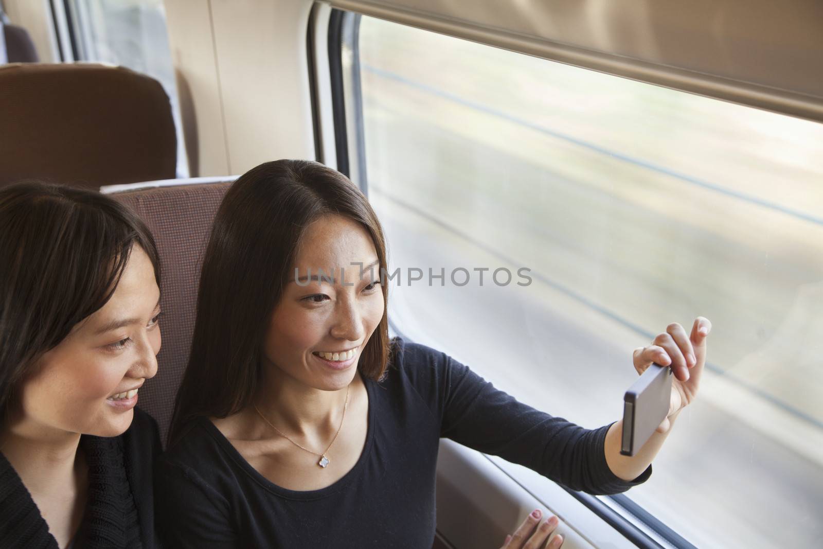 Two Friends Taking a Picture Out the Train Window