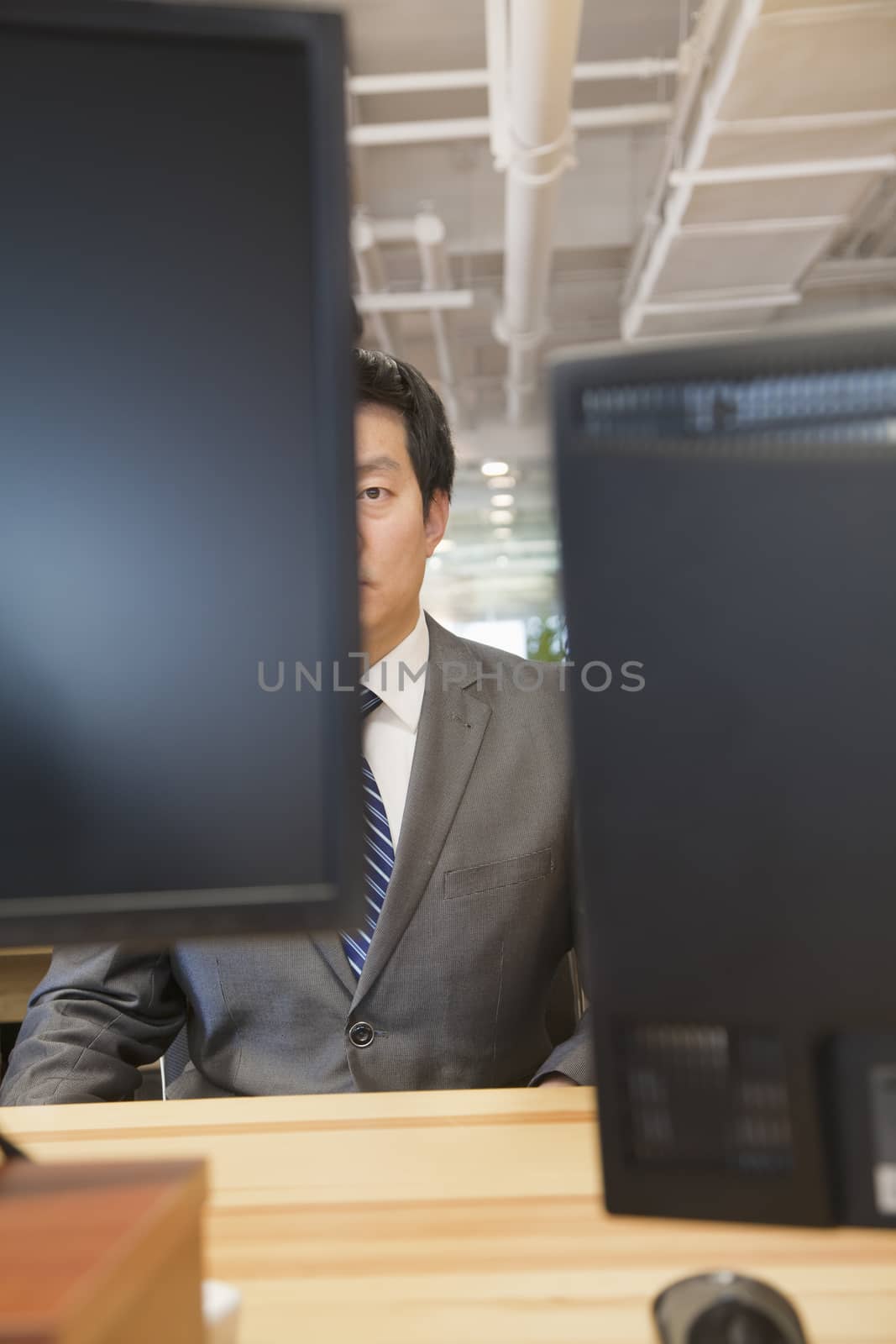 Businessman Looking at Computer in the Office by XiXinXing