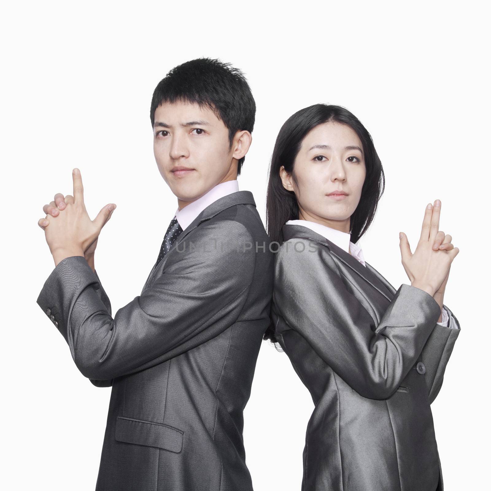 Businessman and businesswoman standing back to back and showing hand guns