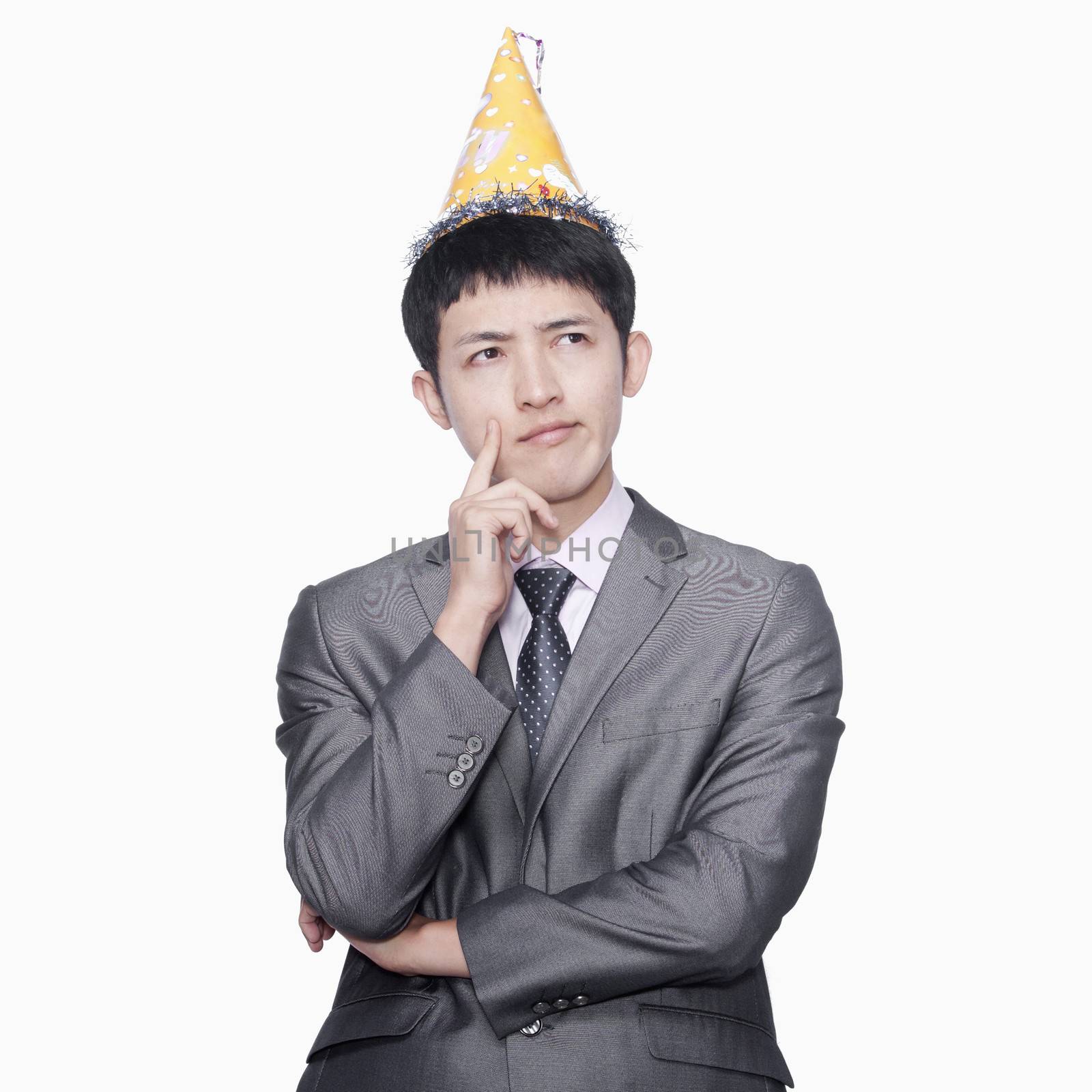 Businessman thinking, wearing party hat by XiXinXing