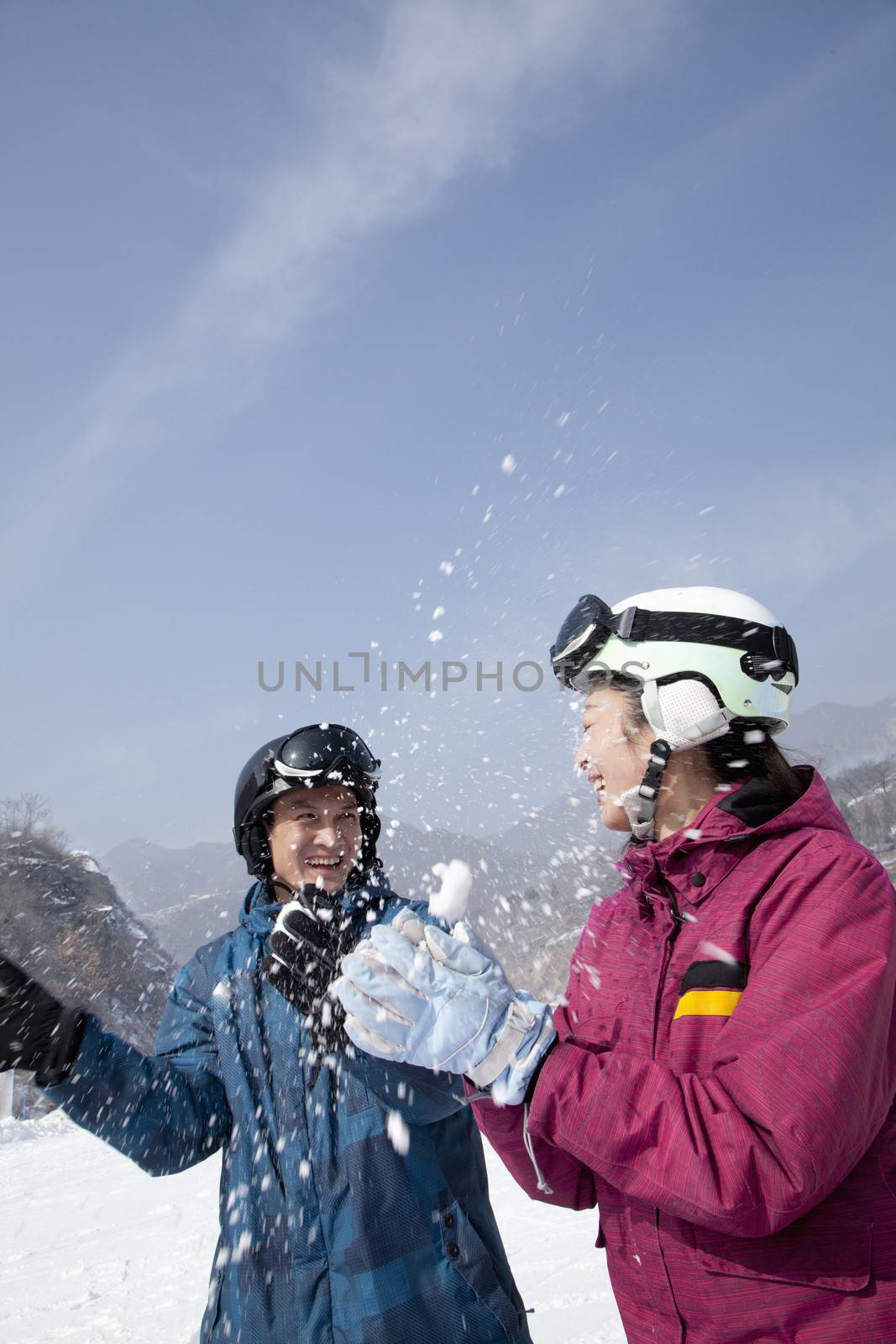 Young Man and Woman Playing in the Snow in Ski Resort by XiXinXing