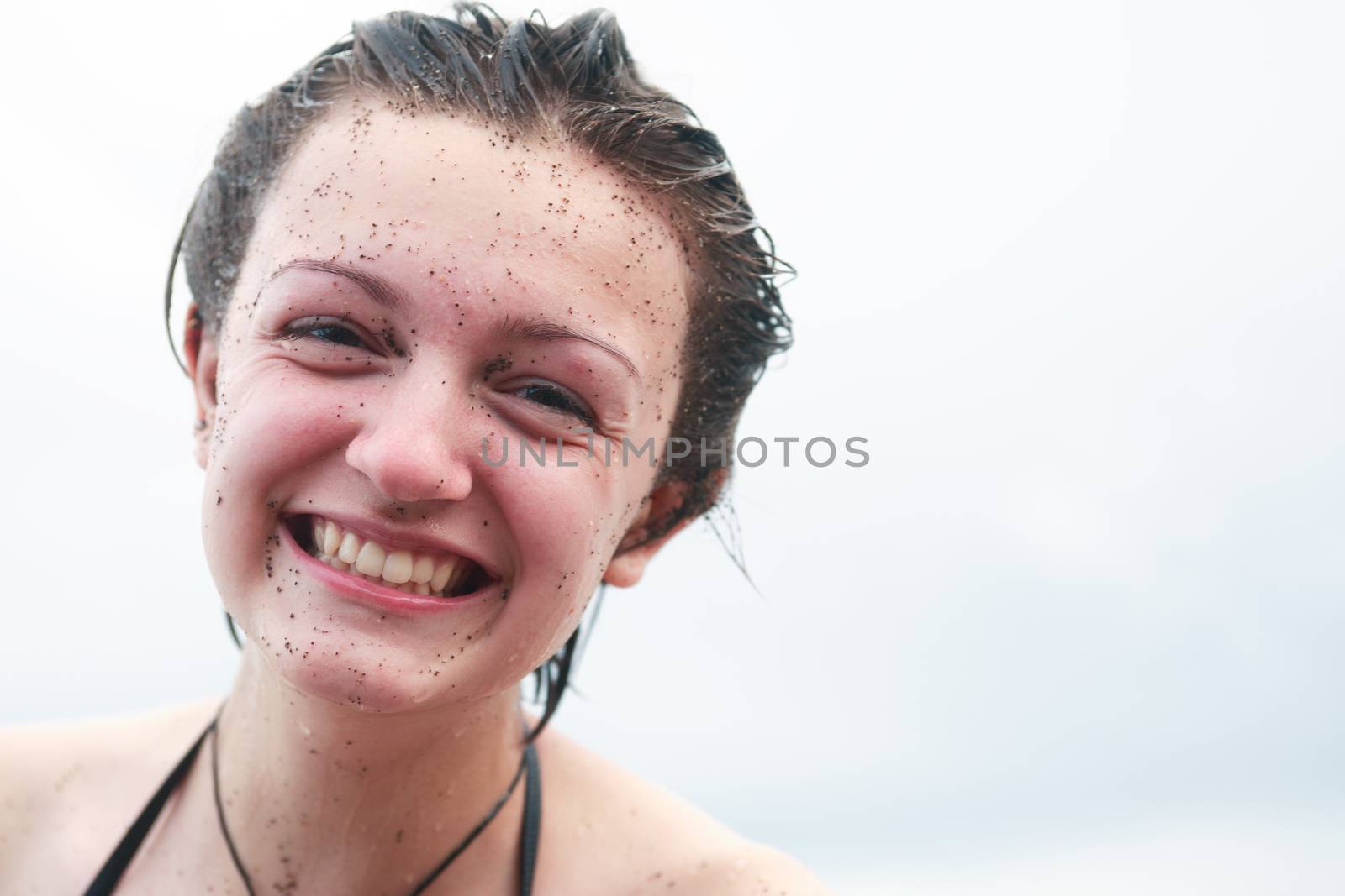 Portrait of smiling teenage girl with sand on her face