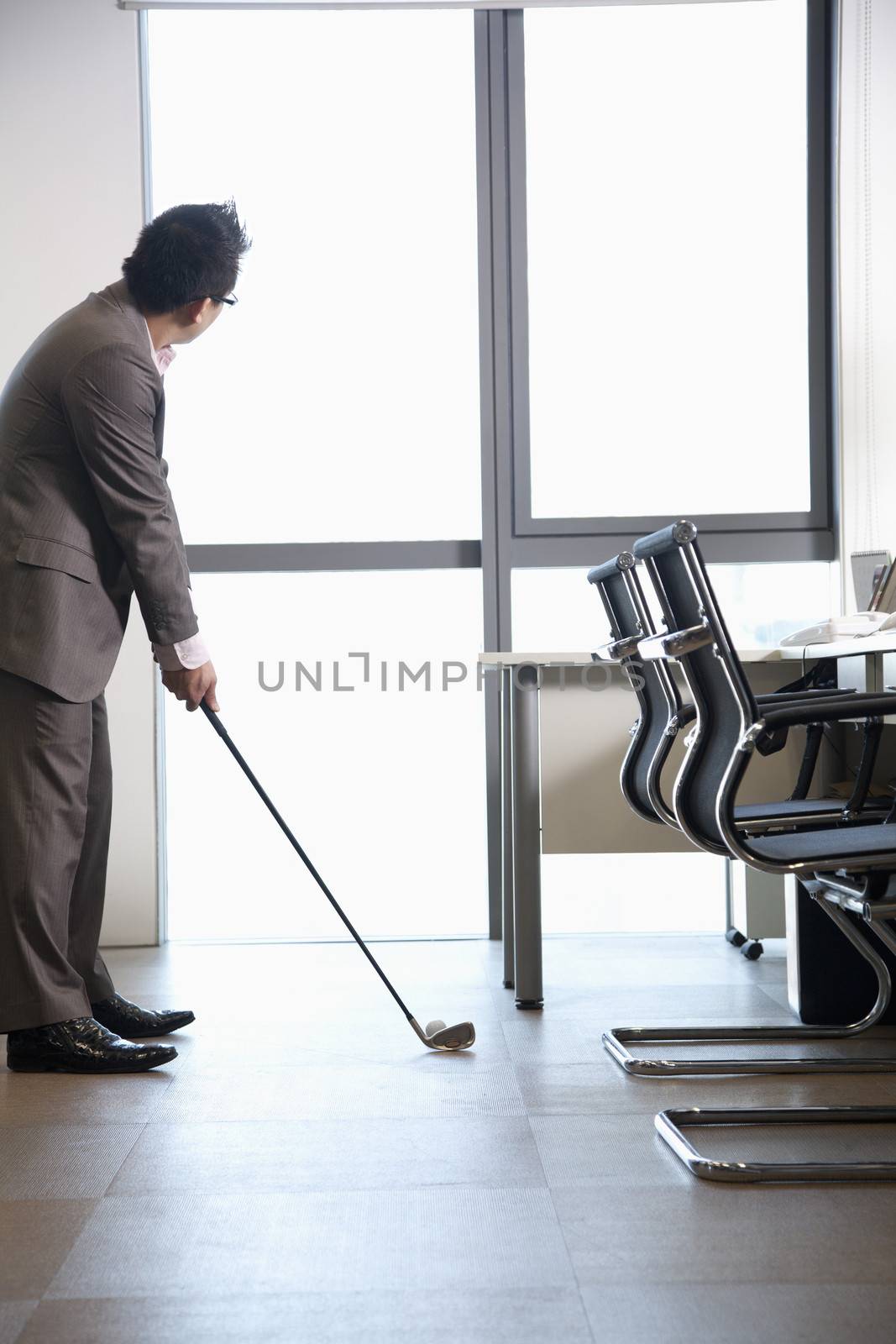 Businessman playing golf in his office