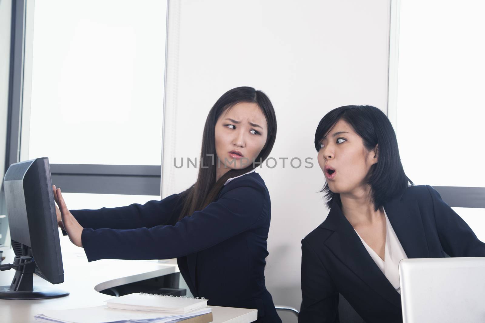 Officer worker hiding her computer from coworker