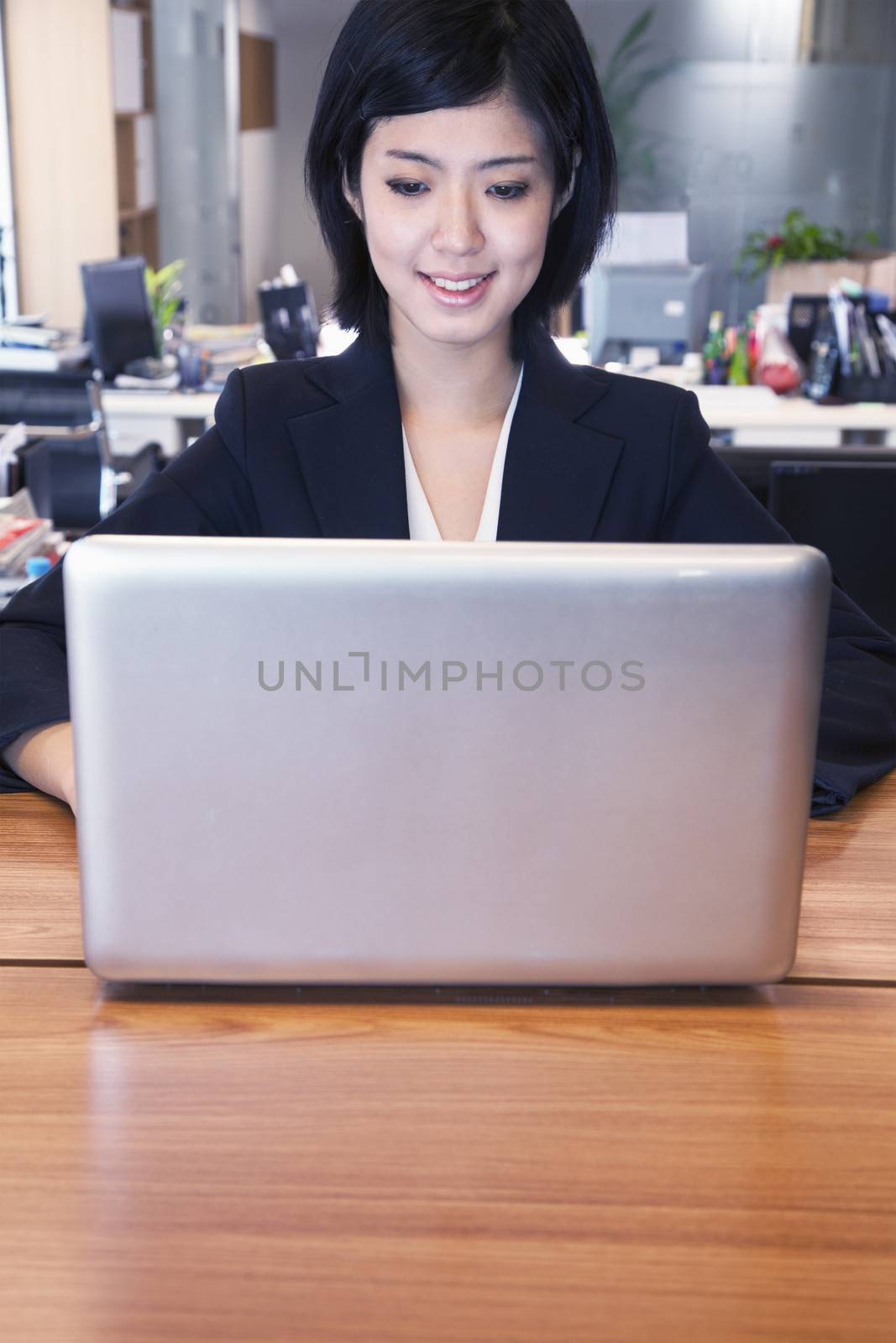 Young businesswoman sitting in front of laptop, portrait