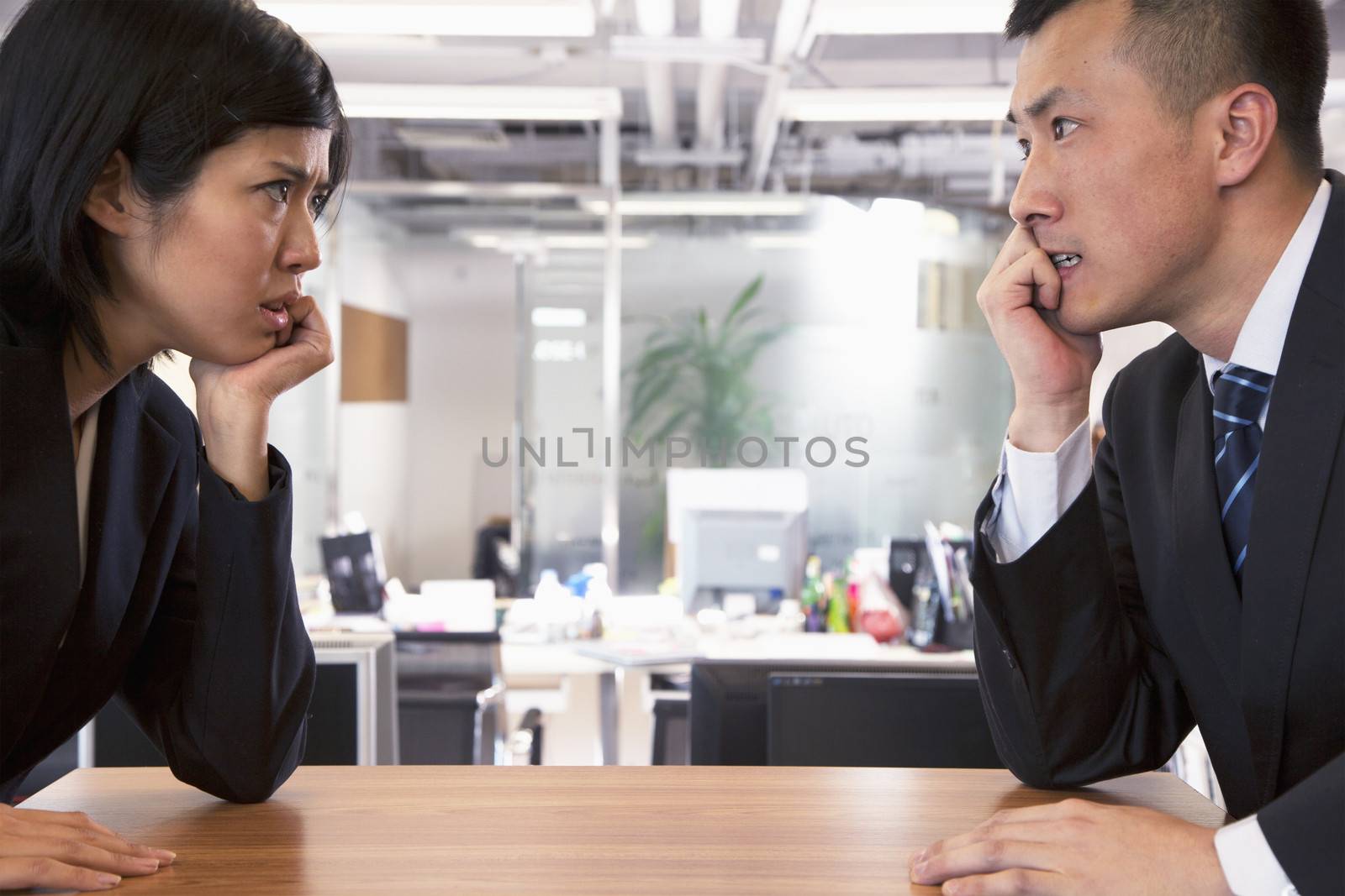 Two Business people staring at each other across a table