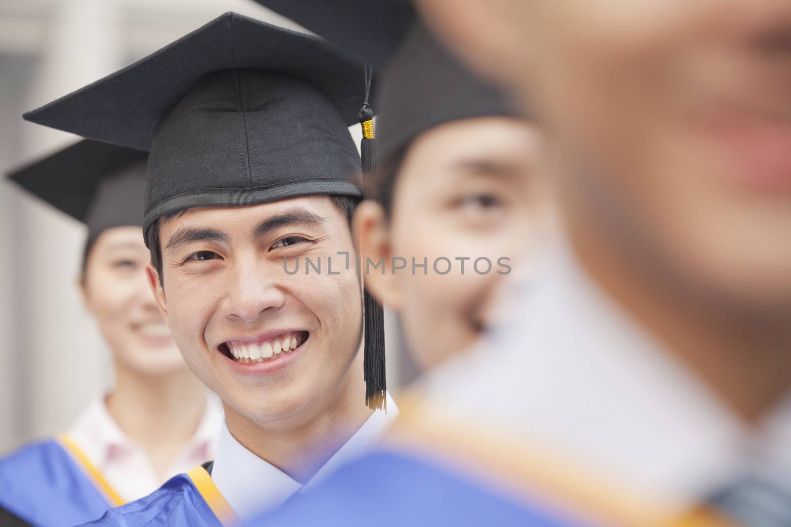 Close Up of Male Graduate Student Standing in a Row of Graduates by XiXinXing