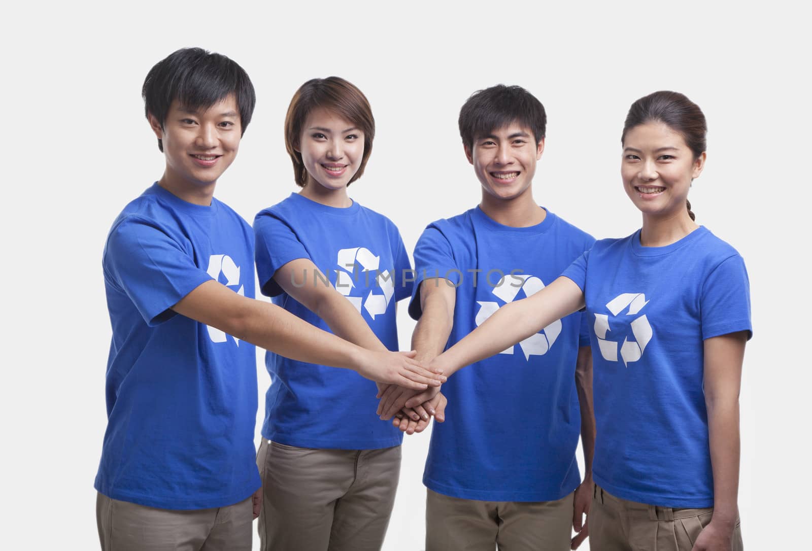Four young people in recycling t-shirts with hands together, studio shot by XiXinXing