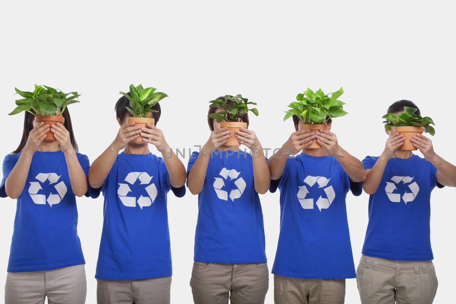 Group of people holding plants, obscuring faces, studio shot