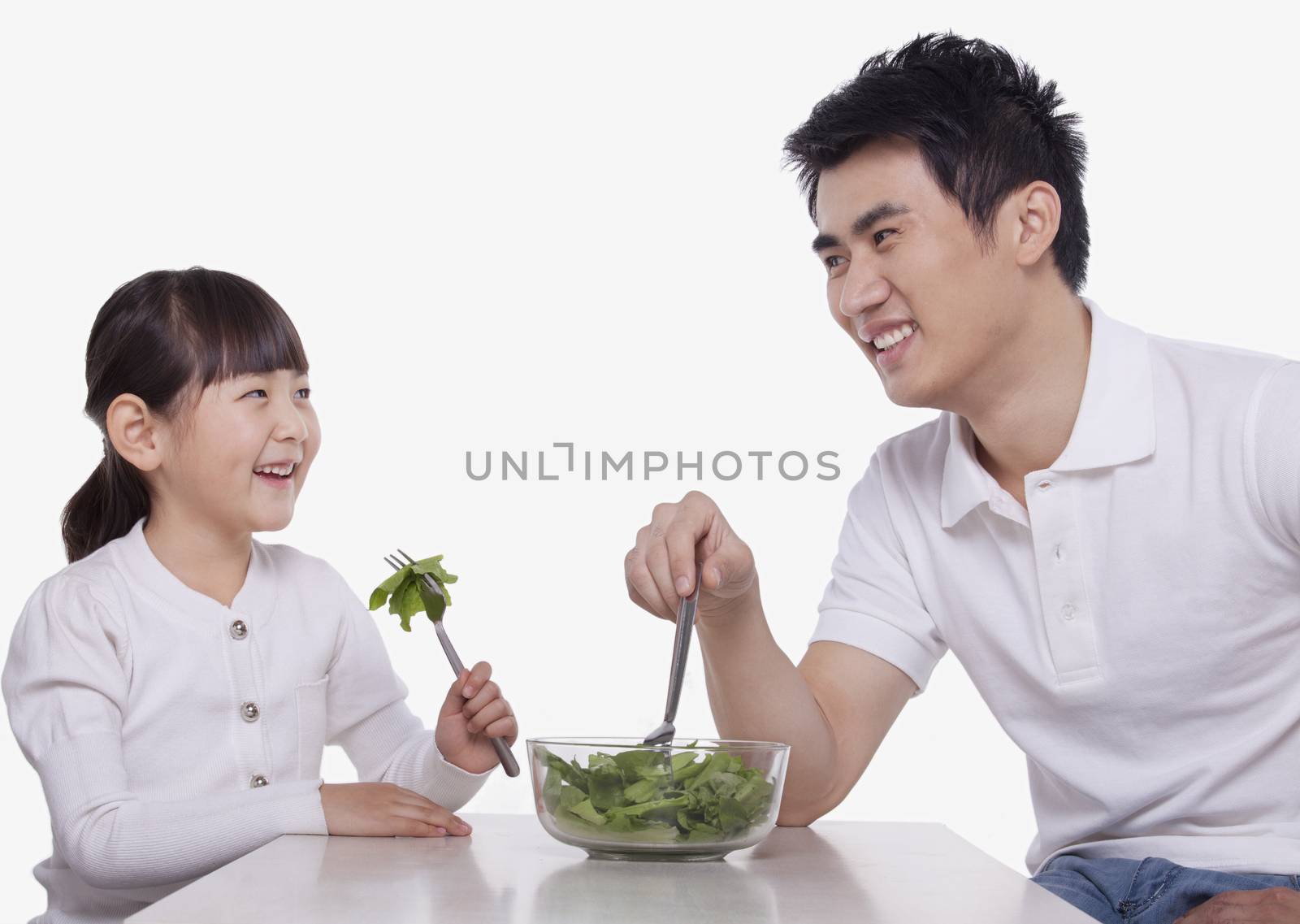 Father and Daughter sharing a salad, studio shot