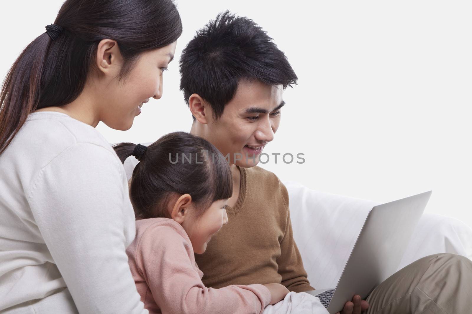 Family sitting on the sofa looking at laptop, studio shot by XiXinXing