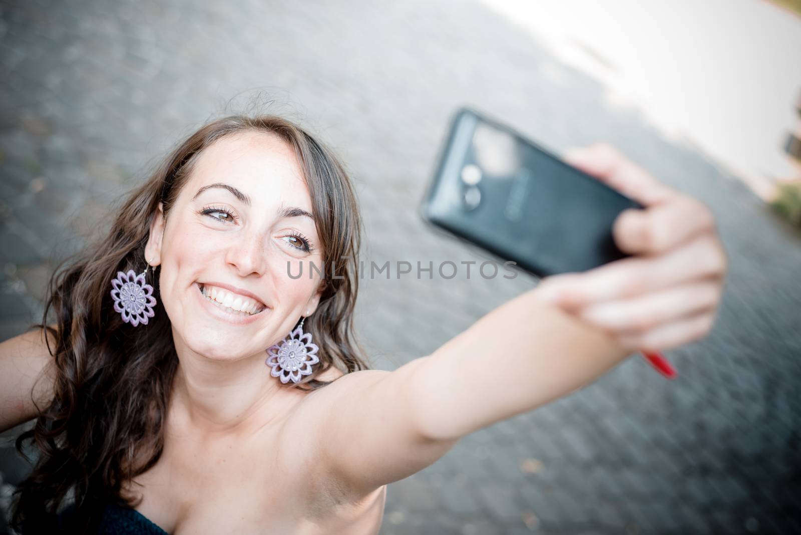 beautiful woman taking self-portrait with smart-phone in the city