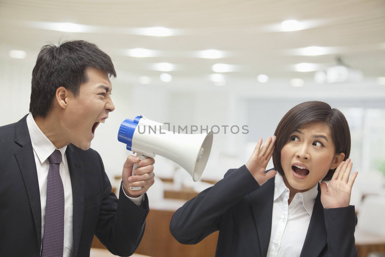 Businessman Talking into Megaphone by Businesswoman's Ear