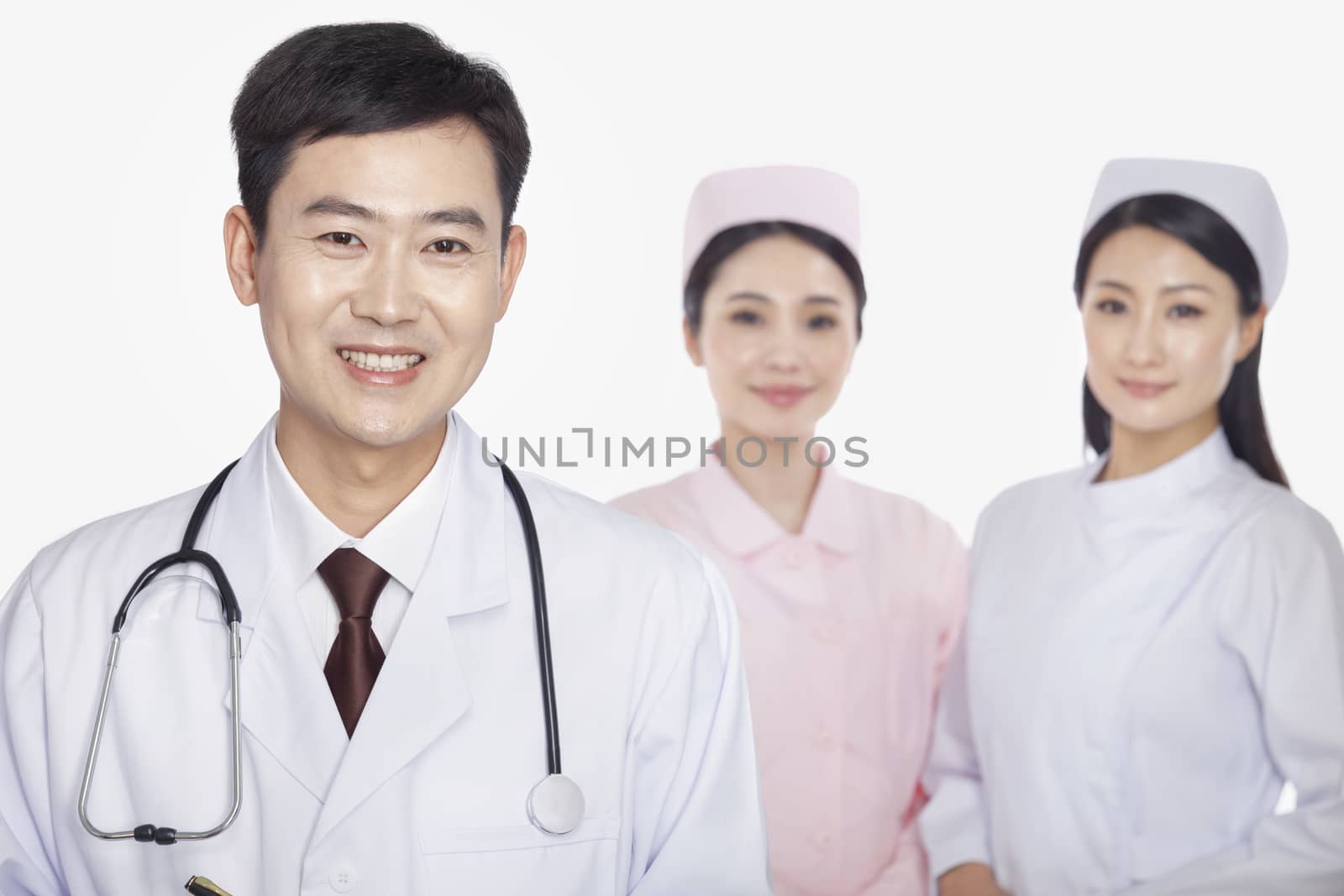 Portrait of doctor, young nurses in background, studio shot by XiXinXing