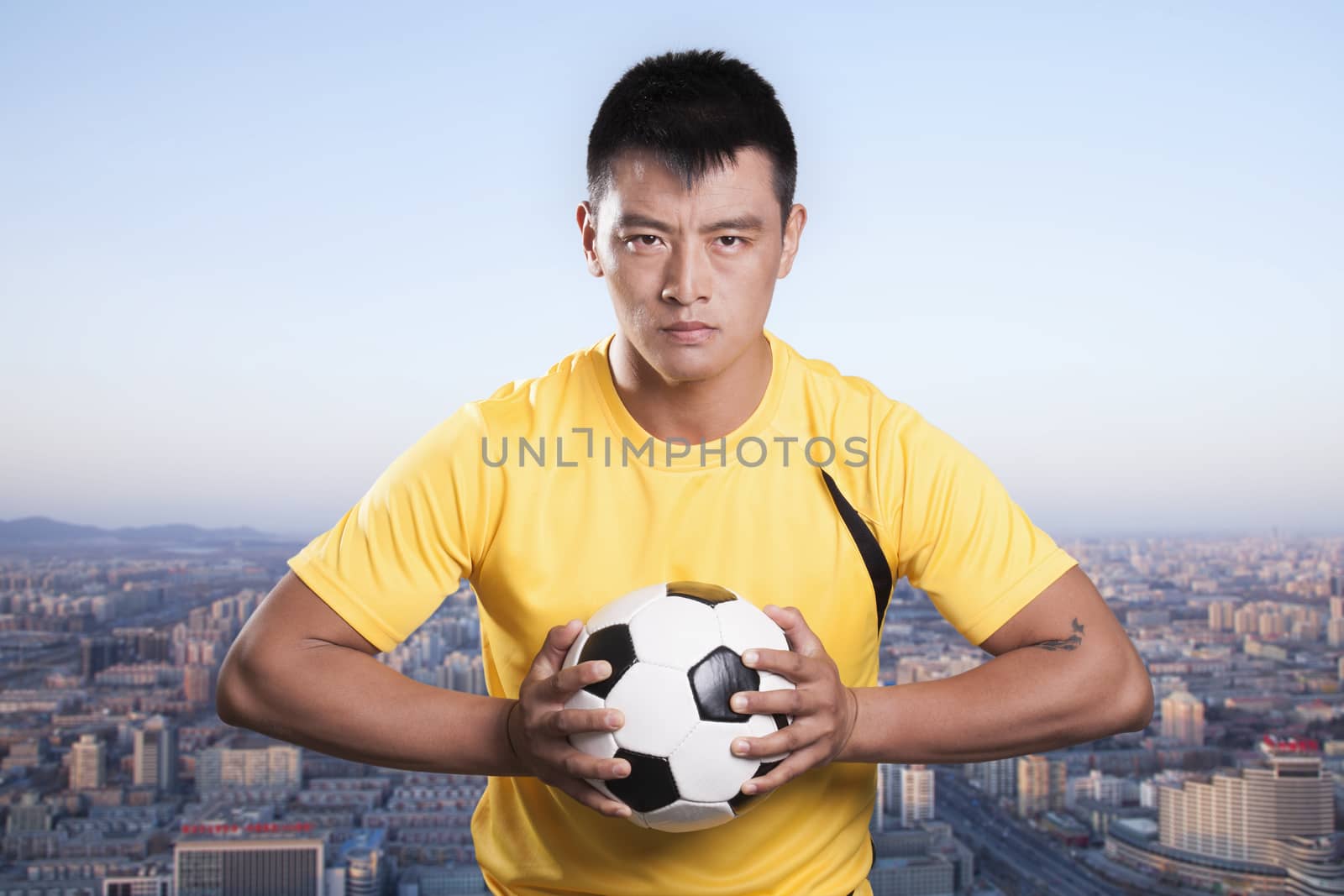 Footballer holding ball to chest, cityscape background