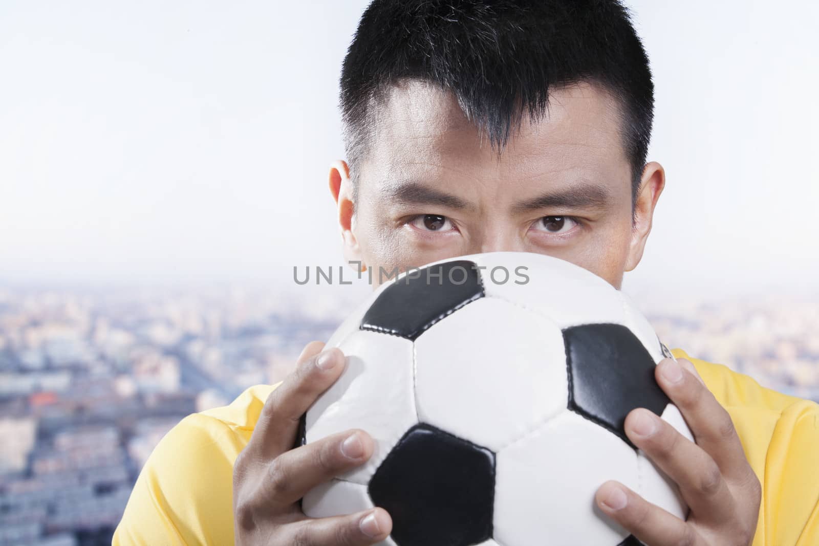 Footballer holding ball against his face