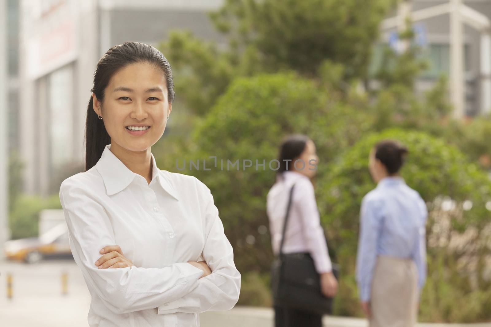 Portrait of smiling young businesswoman with arms crossed, Beijing