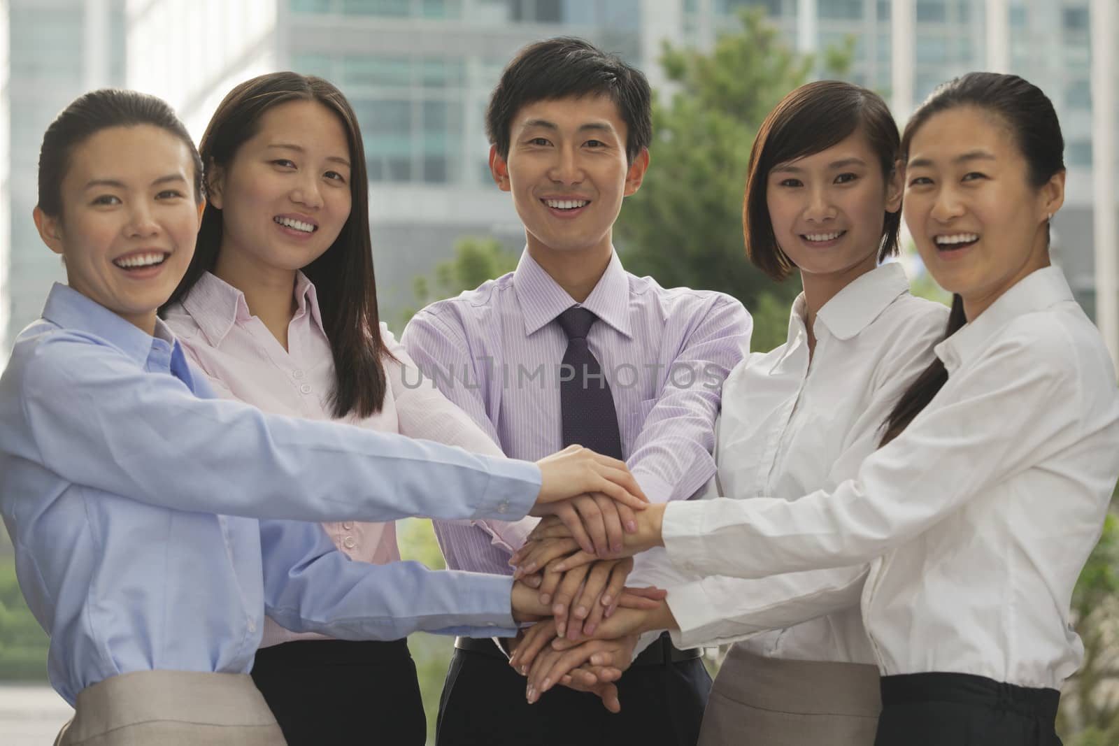 Group of cheerful young business people with hands on top of each other  