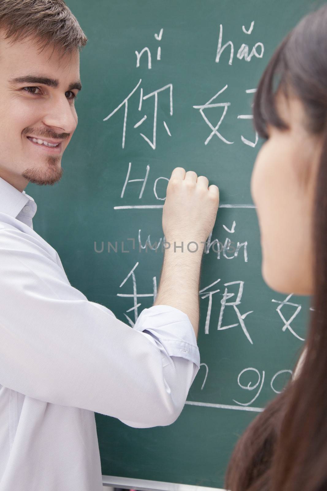 Portrait of smiling male teacher with student in front of chalkboard writing
