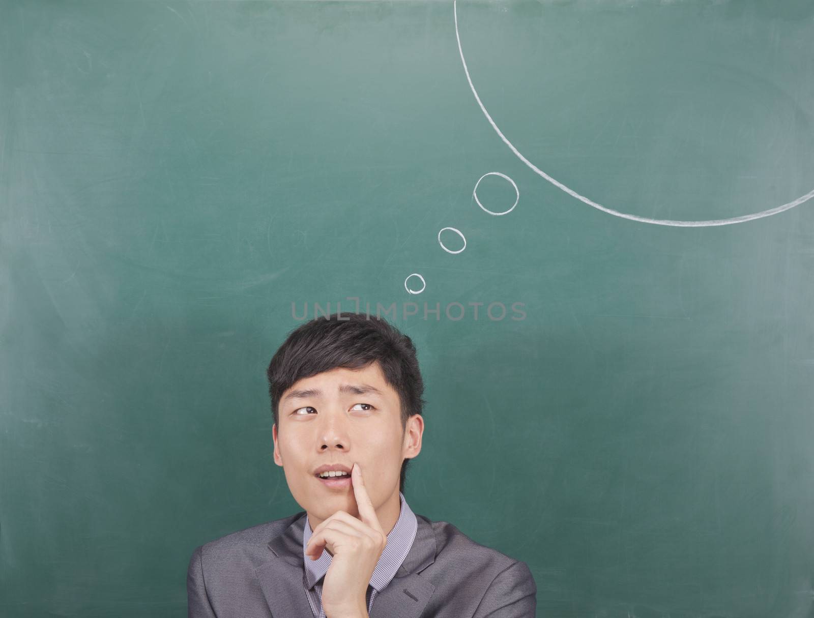 Young man with thought bubble on blackboard