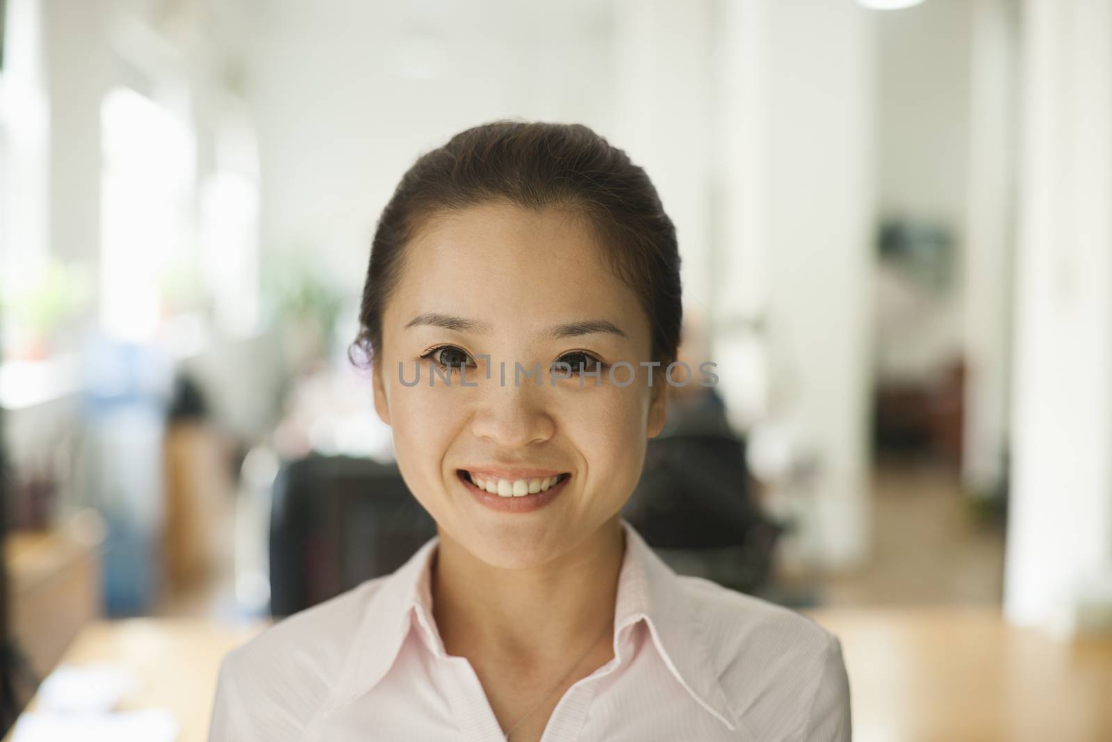 Young woman smiling in the office, portrait by XiXinXing