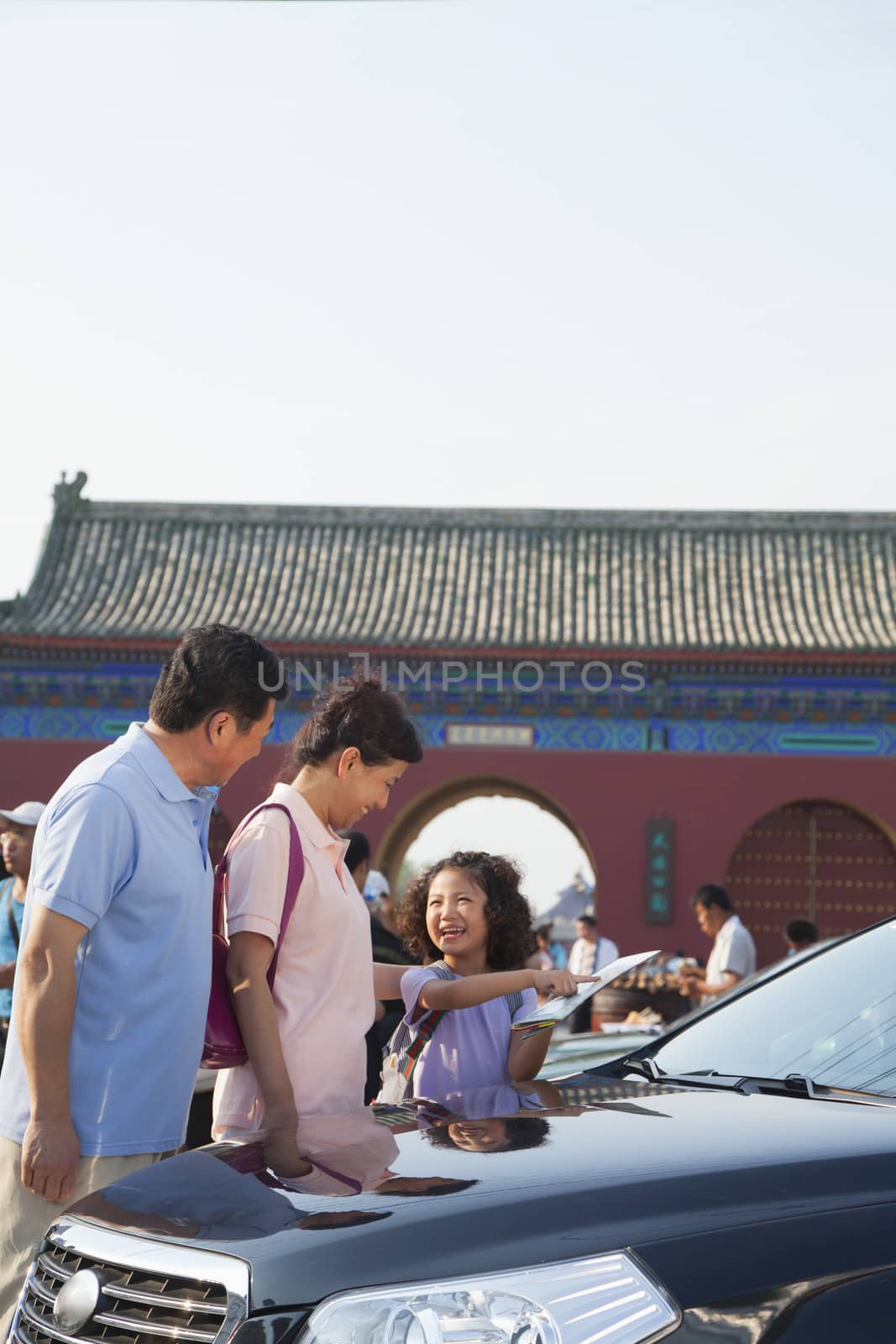 Grandparents and granddaughter standing next to the car and looking at the map by XiXinXing