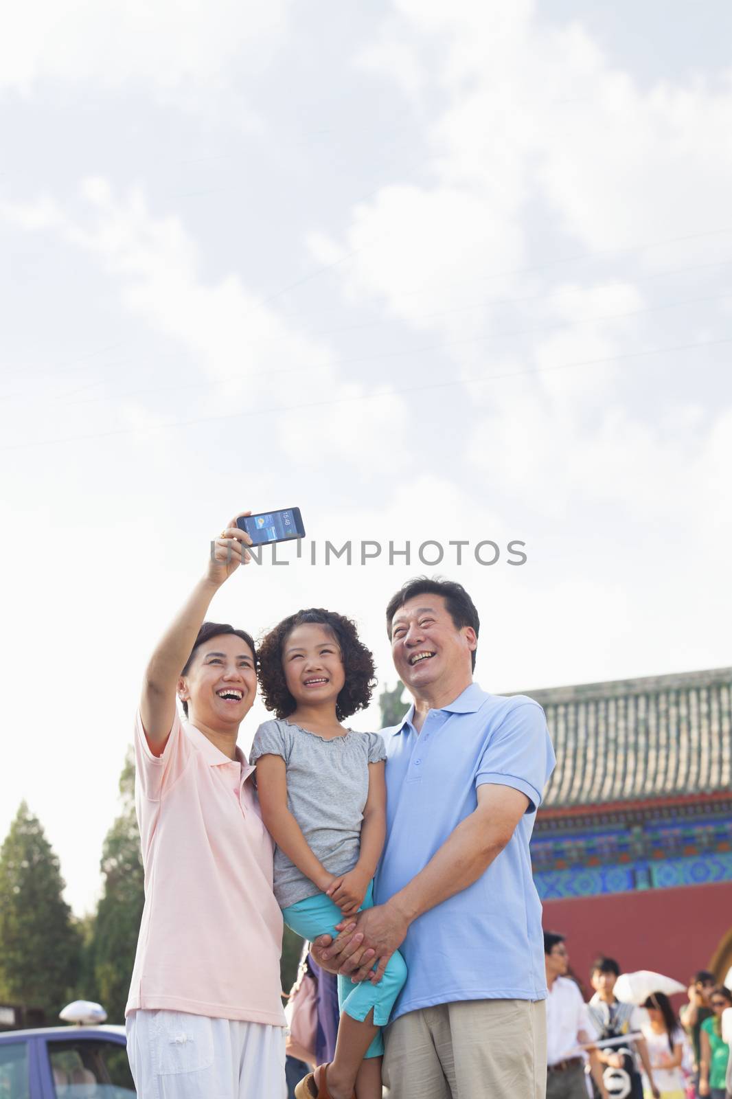 Grandparents and granddaughter taking self portrait with Cell Phone  by XiXinXing