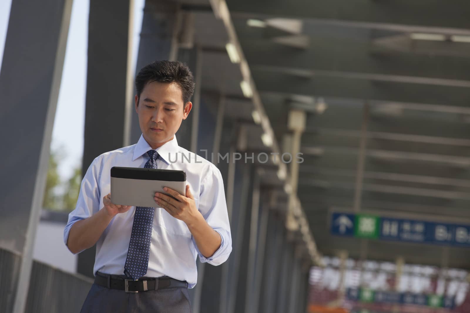 businessman working on his digital tablet near the subway station 