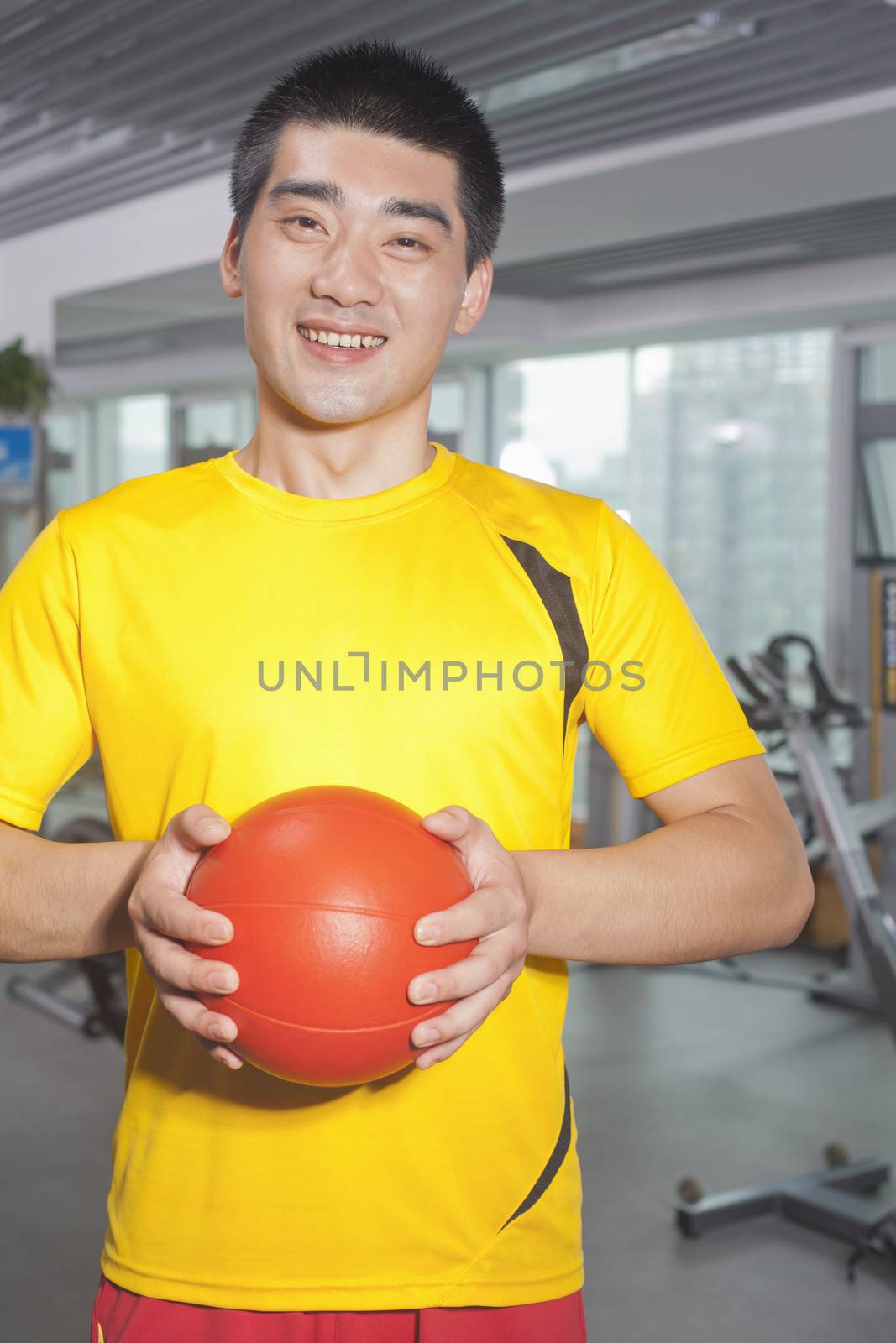 Man holding ball in his hands in the gym 
