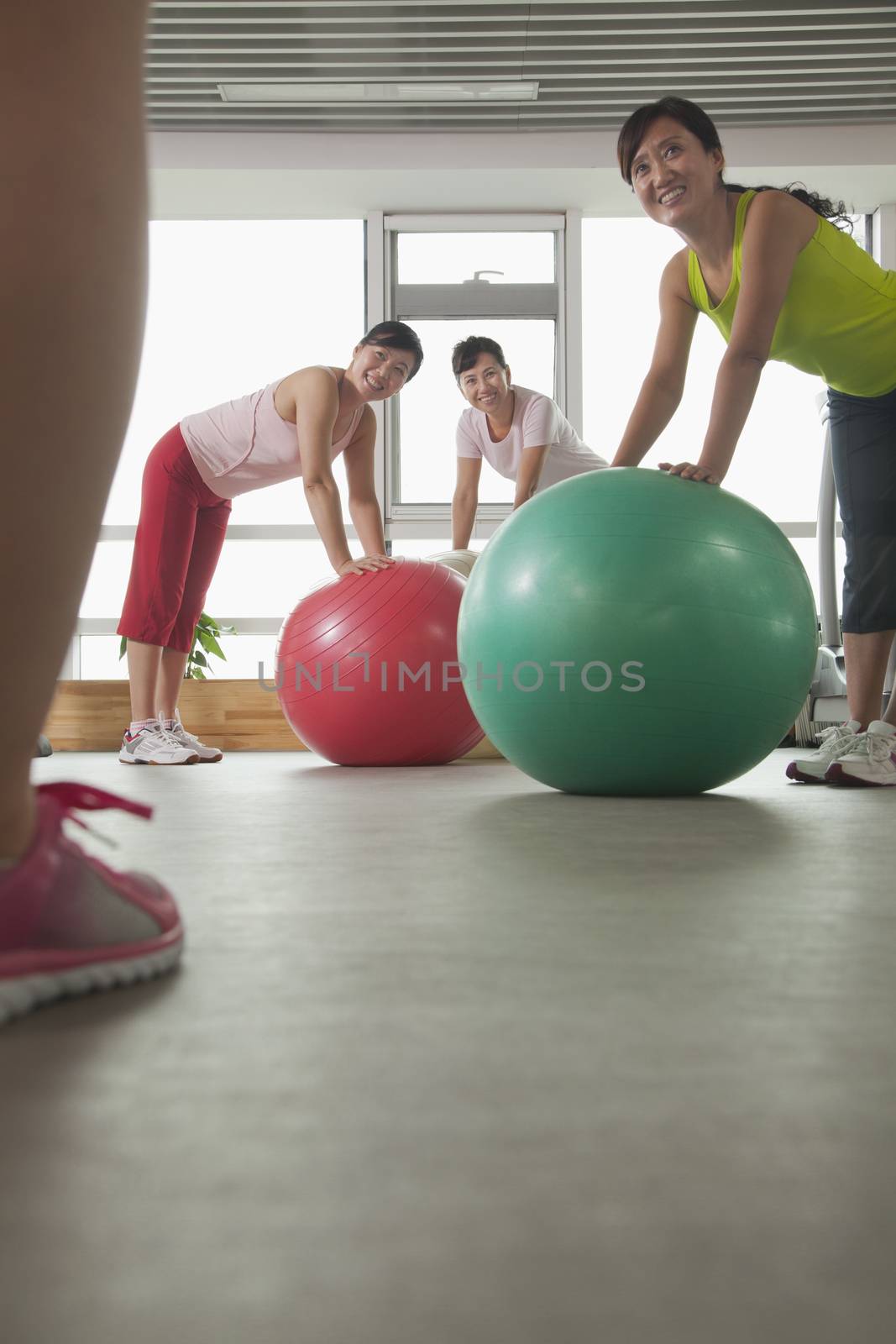 mature women exercising with fitness ball and looking at the trainer by XiXinXing