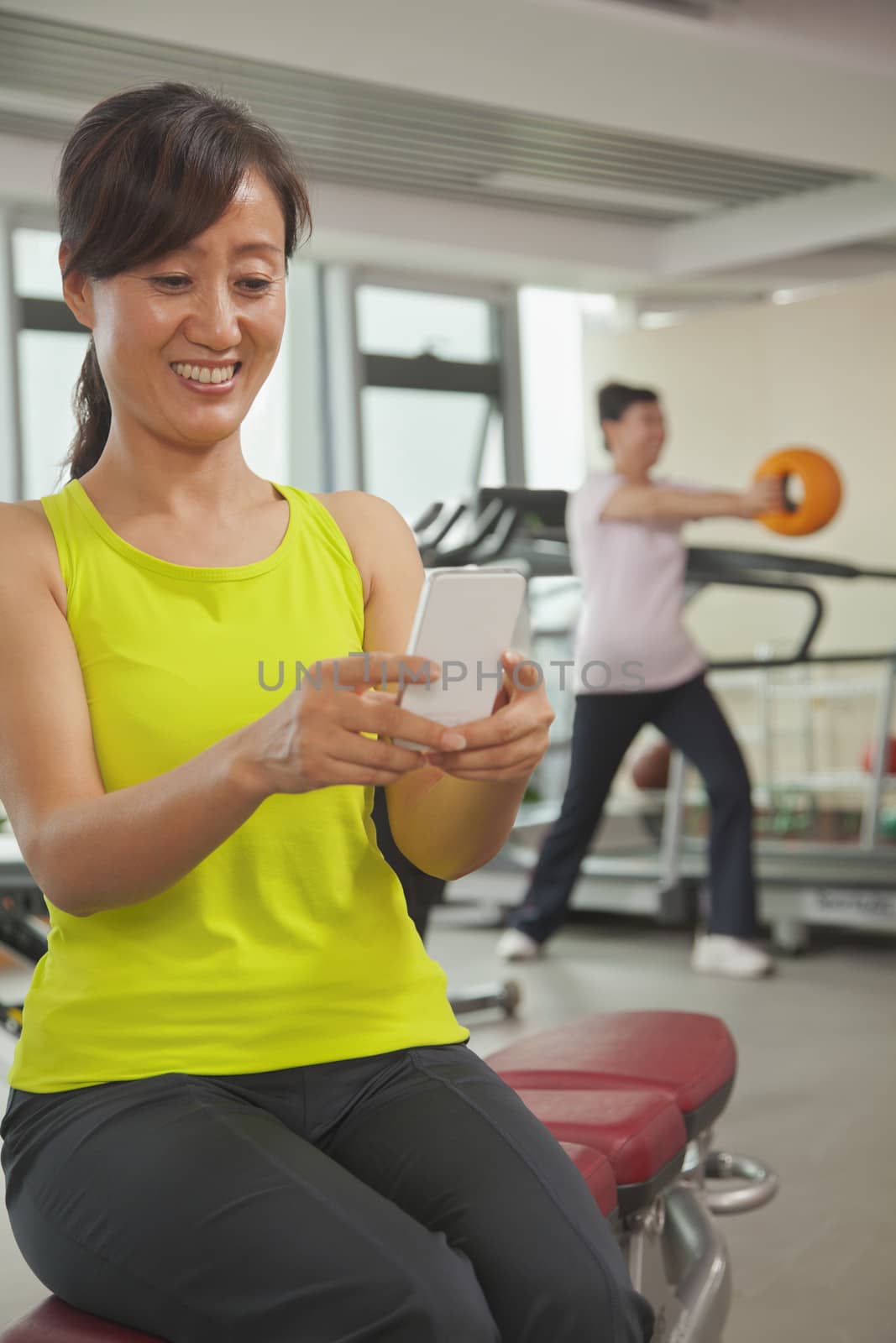 Mature woman using her cell phone in the gym 