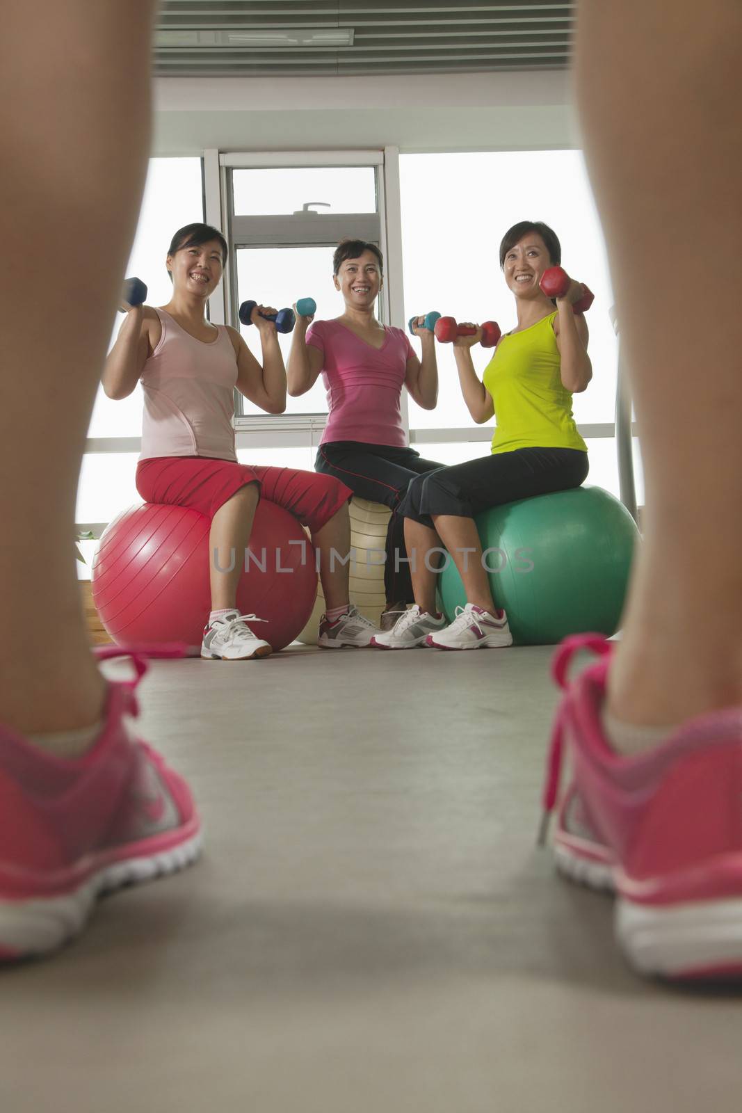 mature women exercising with fitness ball and looking at the trainer