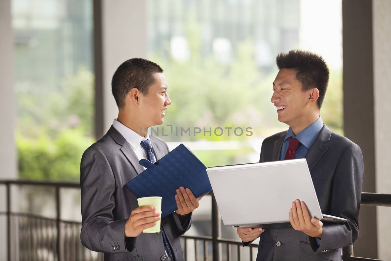 Two young businessmen working outdoor, looking at each other  