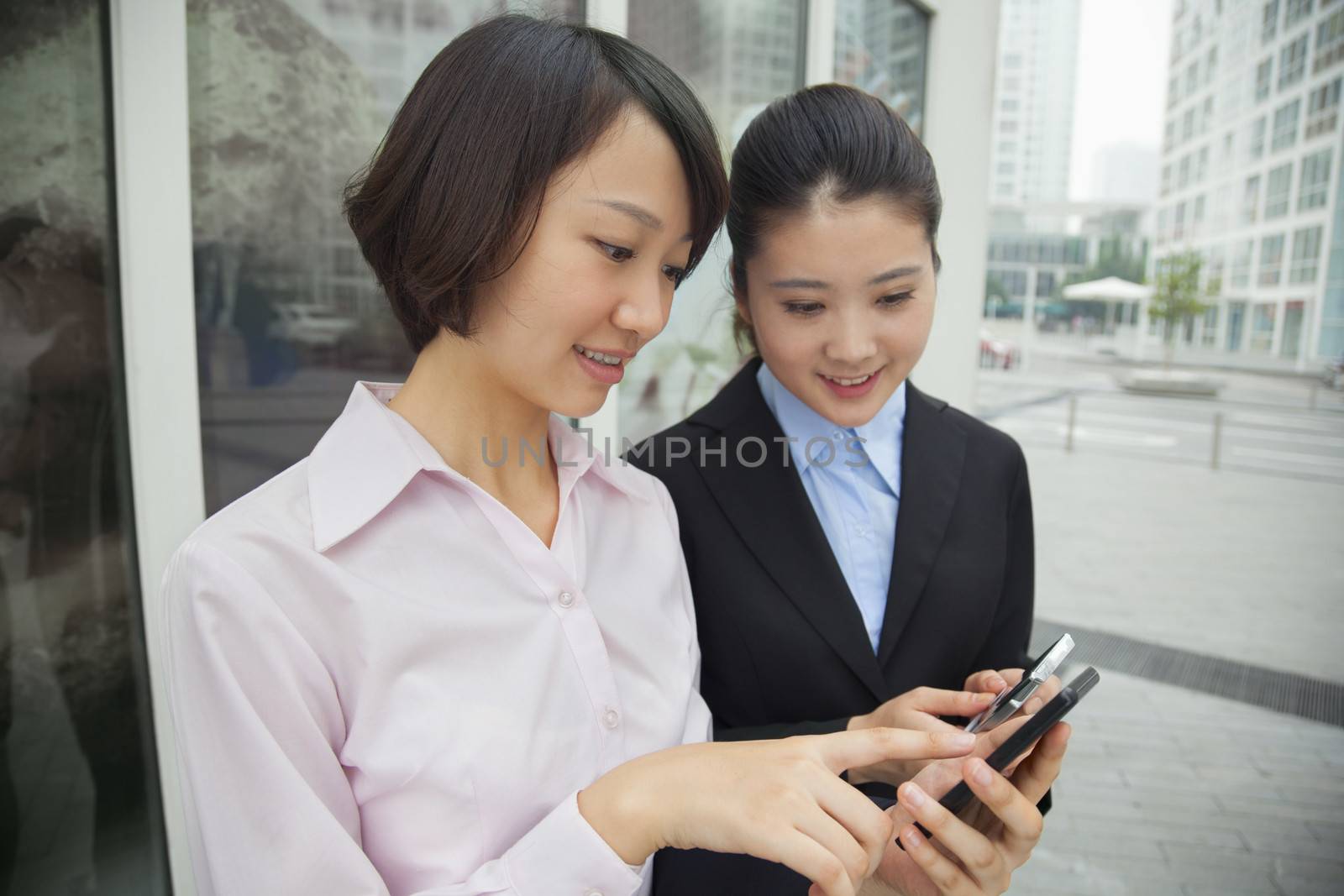 Young businesswomen looking at their cell phones