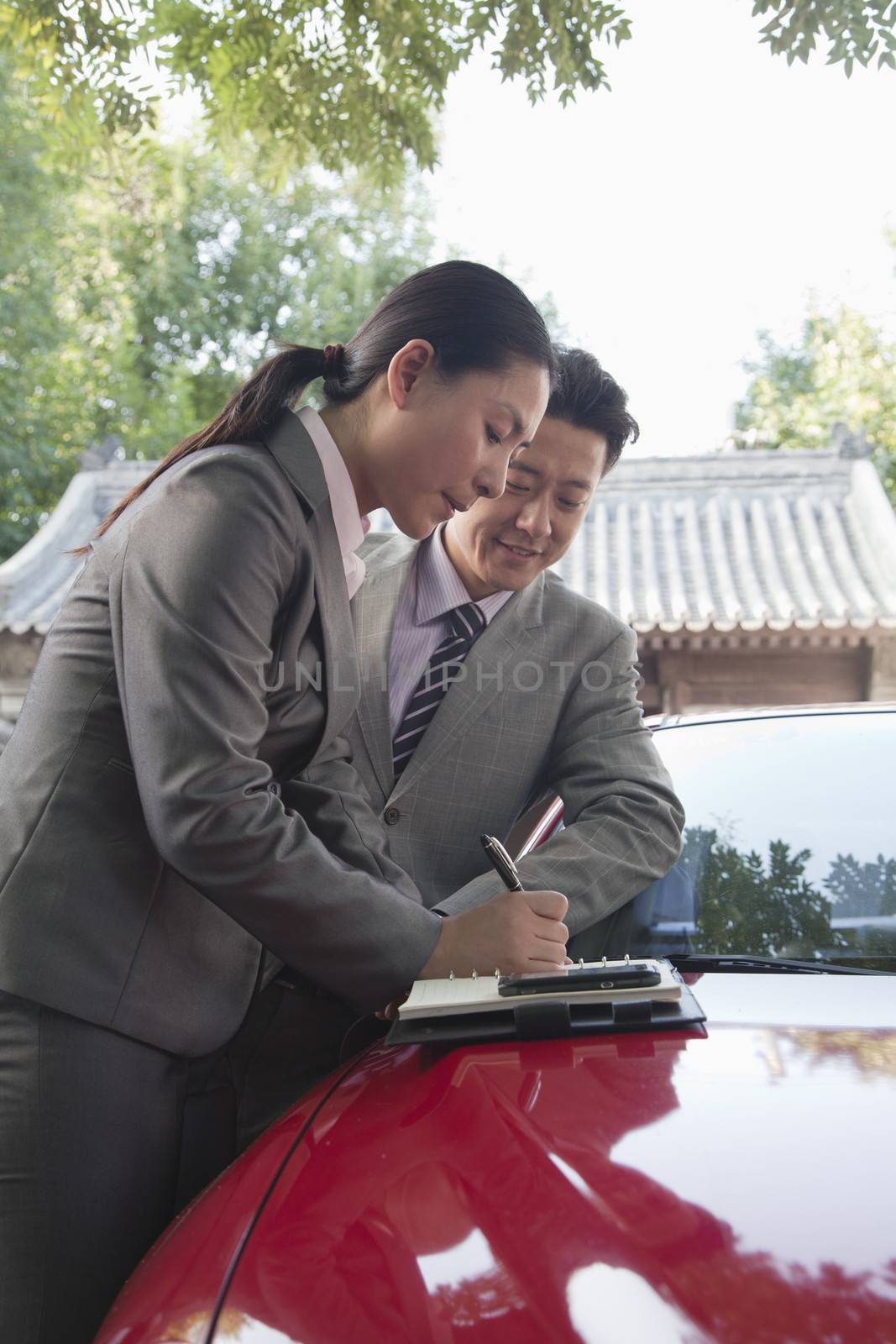 Businesspeople Working Outdoors on the Hood of a Car by XiXinXing