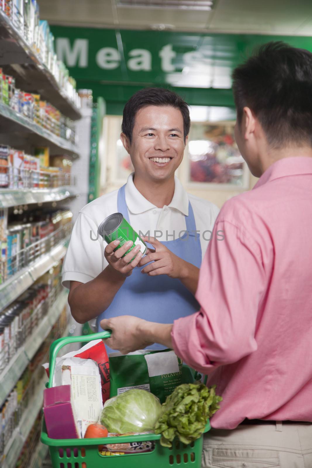 Sales clerk assisting man in supermarket, Beijing by XiXinXing