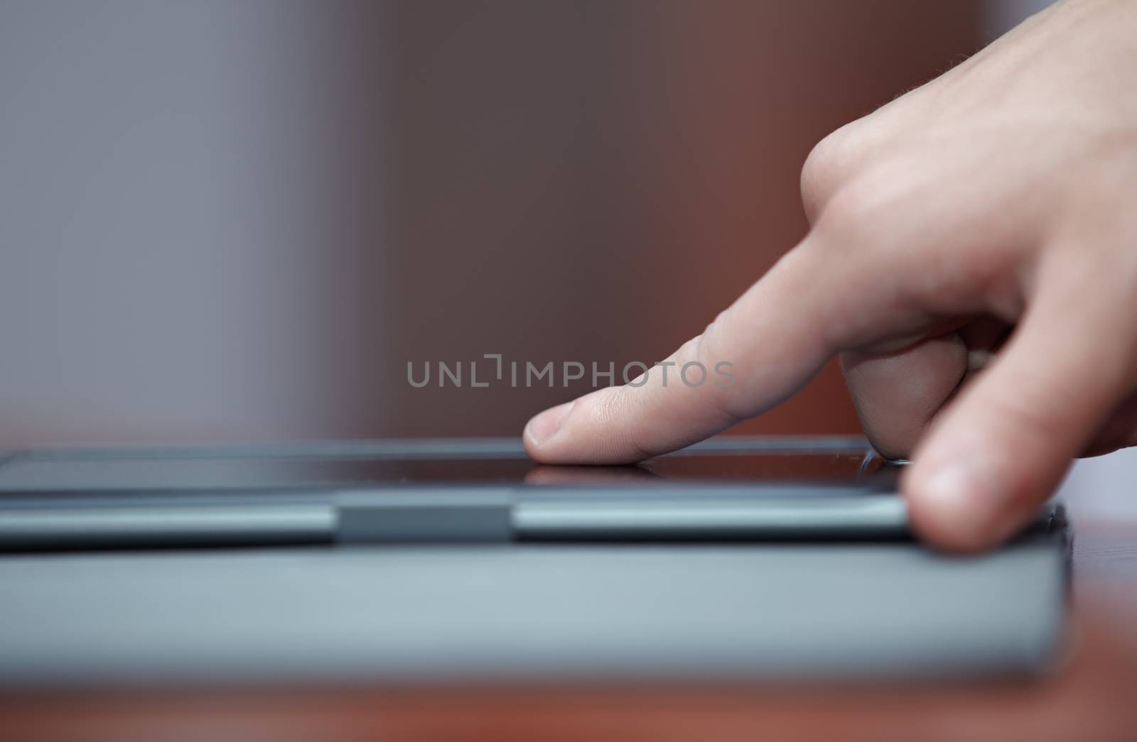 Human hand using tablet computer indoors