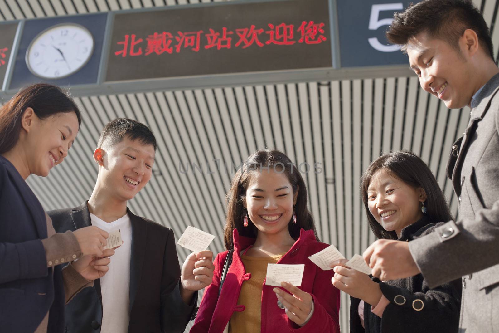 Group of people looking at tickets at the railway station by XiXinXing