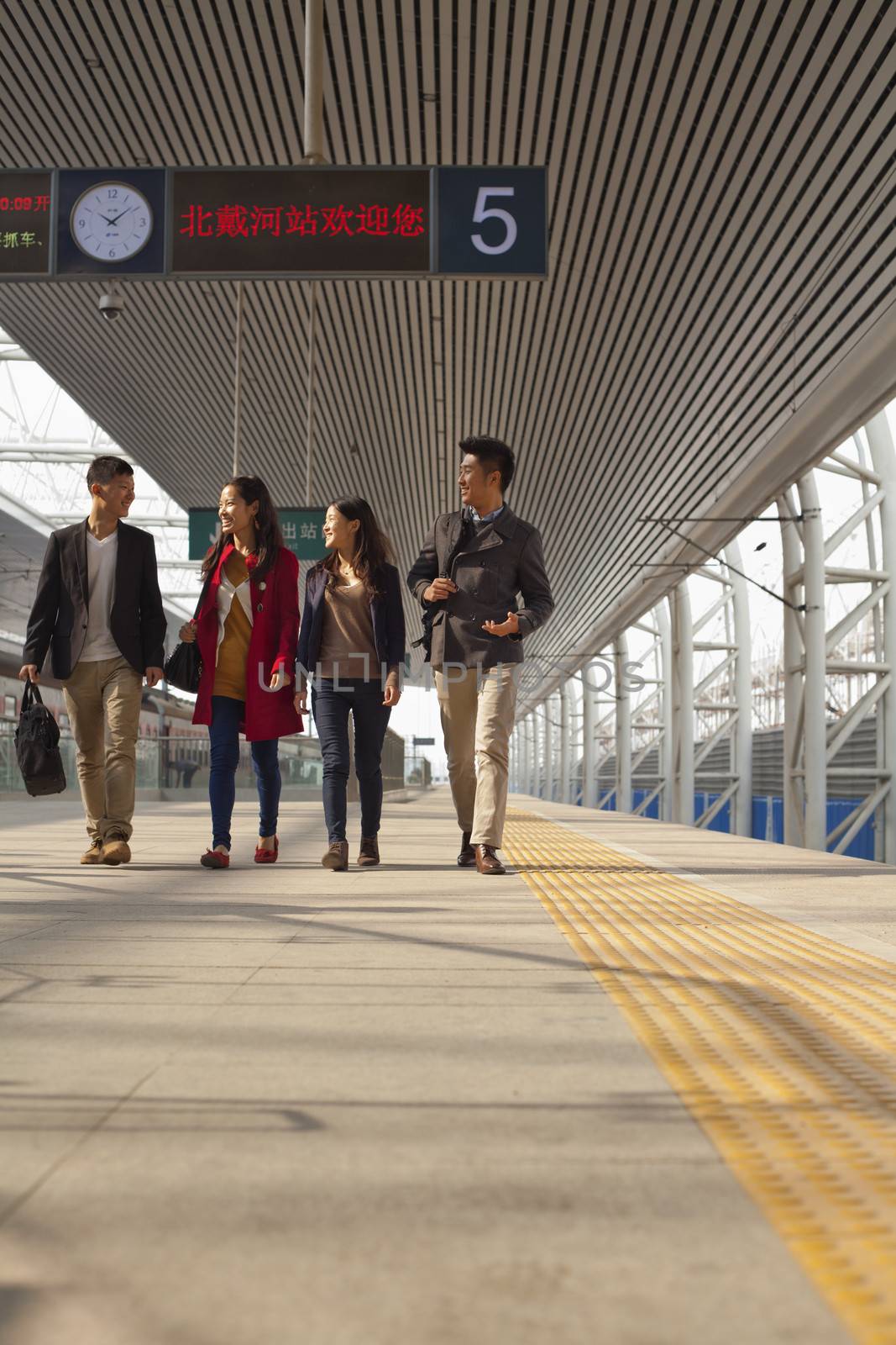 Group of young people talking on railway platform by XiXinXing