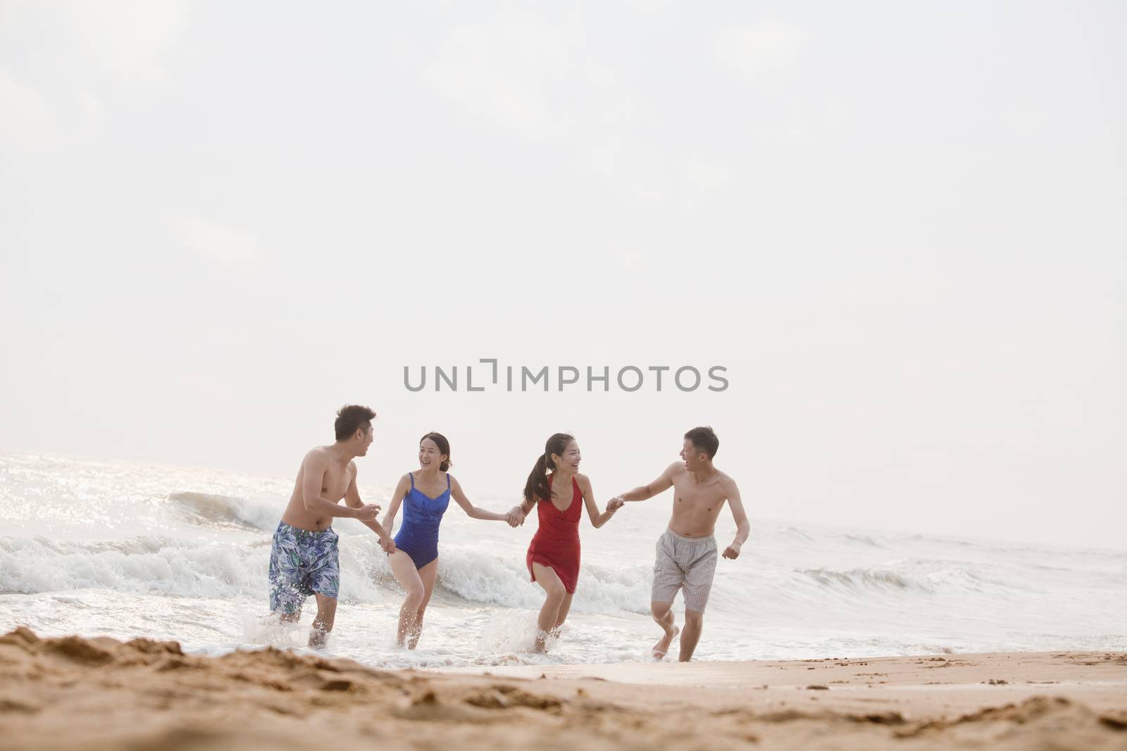 Four friends running out of the water on a sandy beach by XiXinXing