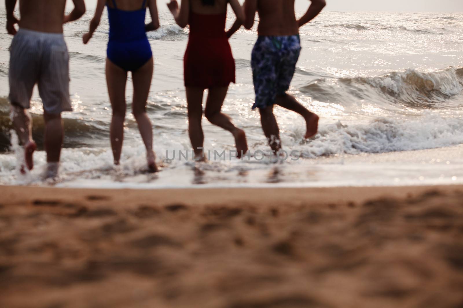 Four friends running into the water on a sandy beach, Silhouette by XiXinXing