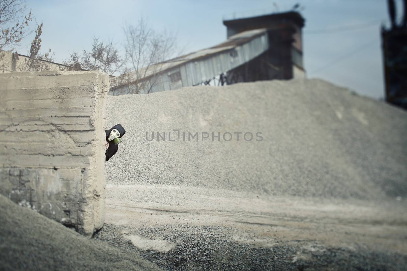 Human in the gas mask playing hide-and-seek at the industrial plant