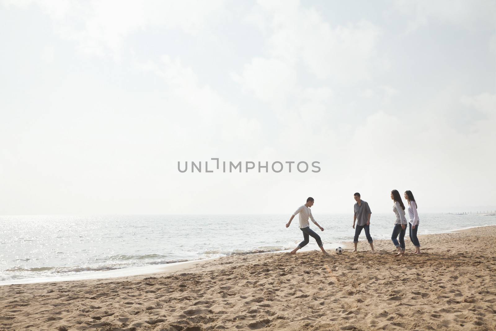 Young Friends Playing Soccer on the Beach by XiXinXing