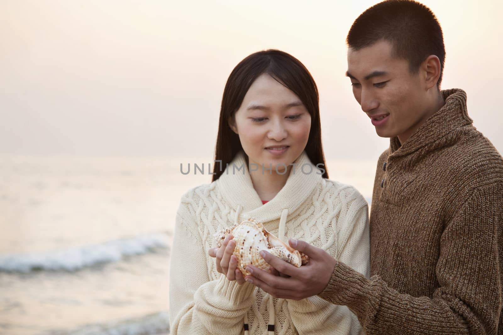 Young Couple Looking At a Seashell by XiXinXing