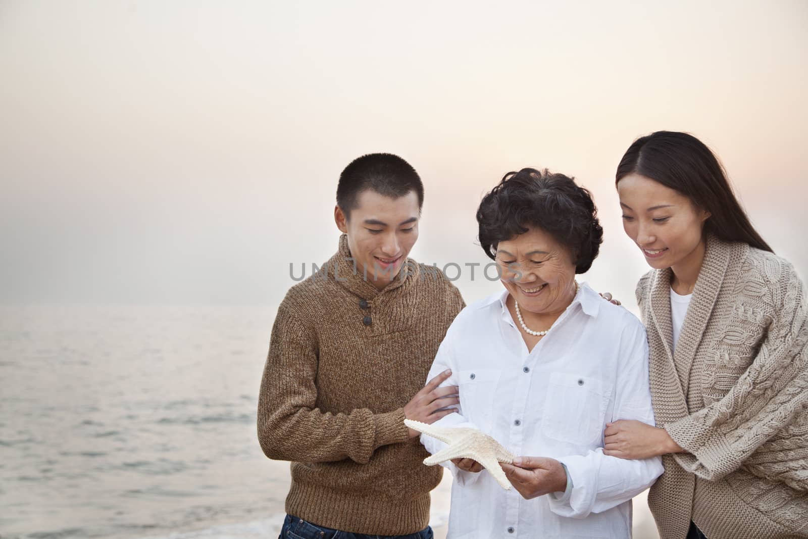 Grandmother and Grandchildren Looking At Starfish by XiXinXing
