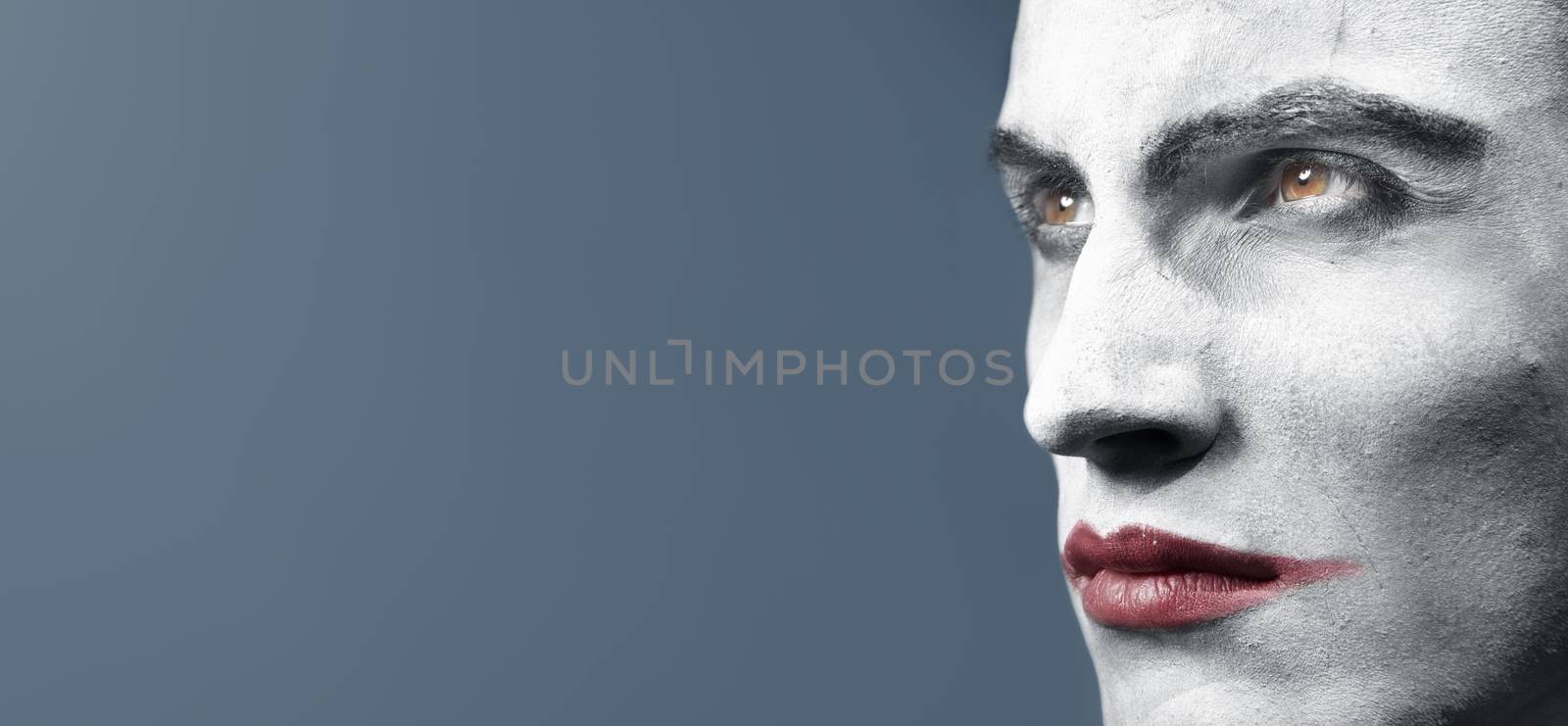 Male head with face-paint outdoors during twilight. Creative colors and darkness added. Horizontal photo with empy space
