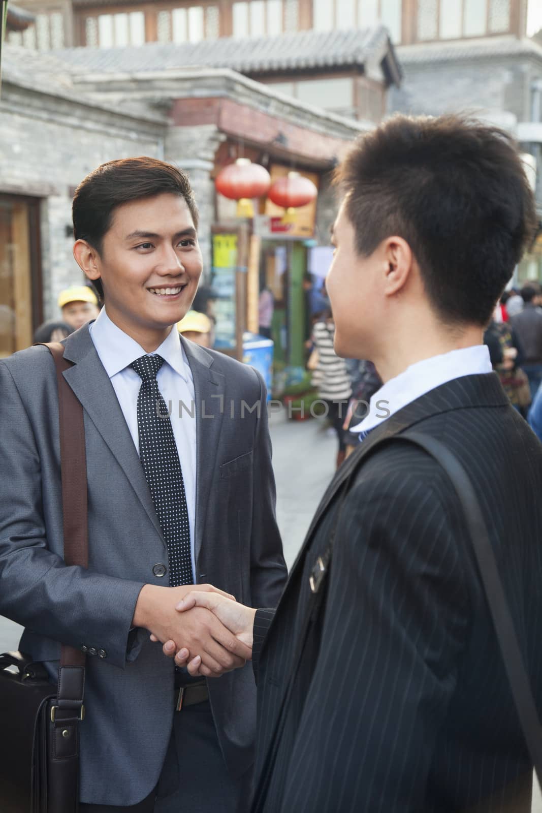 Two young businessman handshaking in houhai, Beijing, China