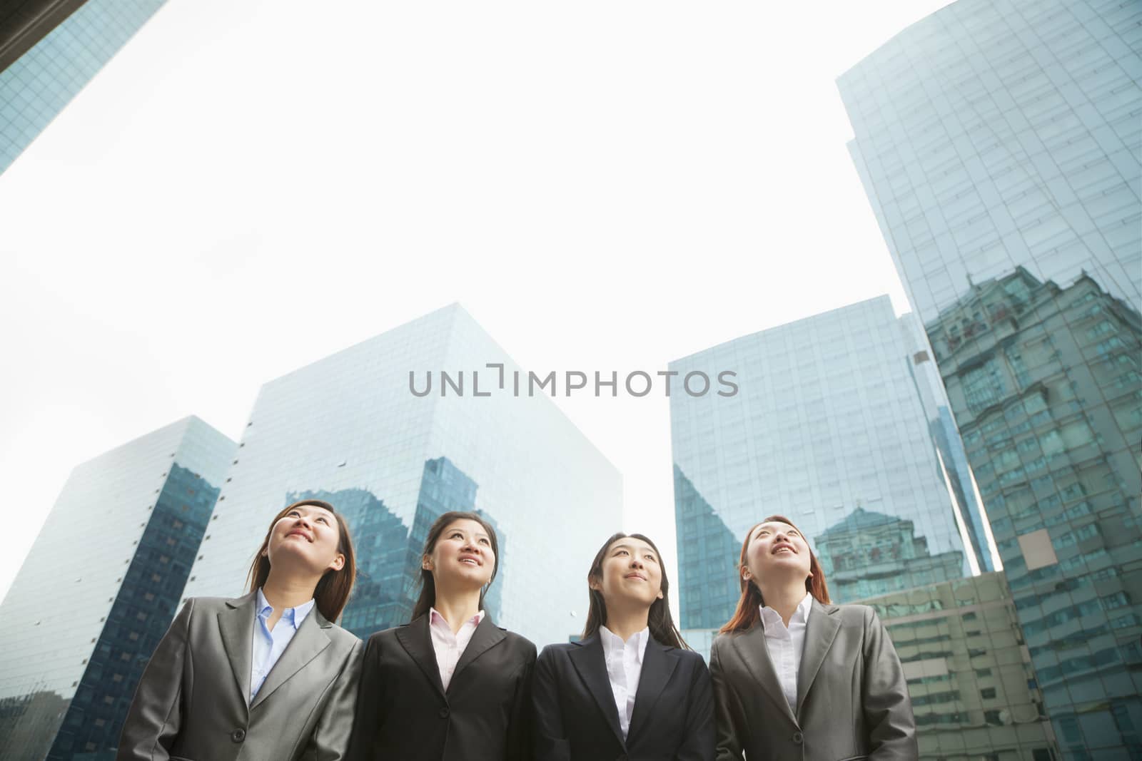 Group of young businesswomen standing in a row among skyscrapers, Beijing by XiXinXing