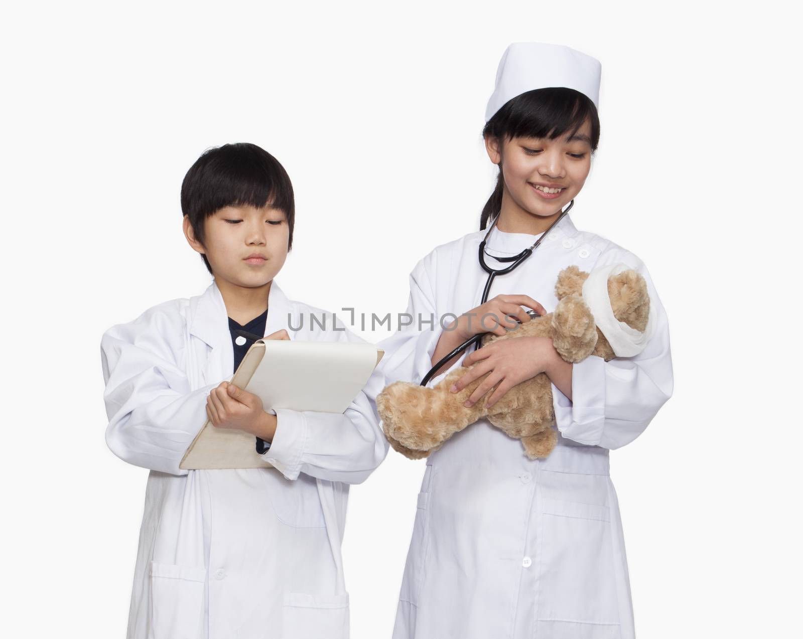 Boy and girl dressed up as doctors checking teddy bear's vital signs by XiXinXing