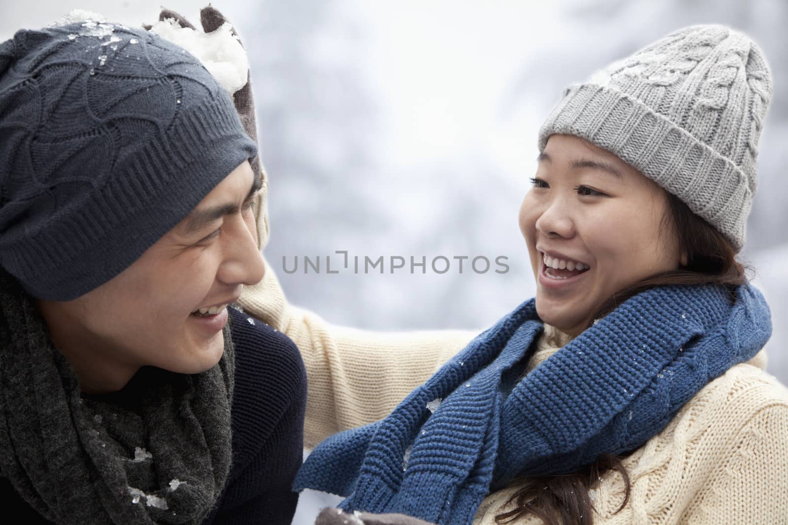 Young Couple Having a Snowball Fight by XiXinXing